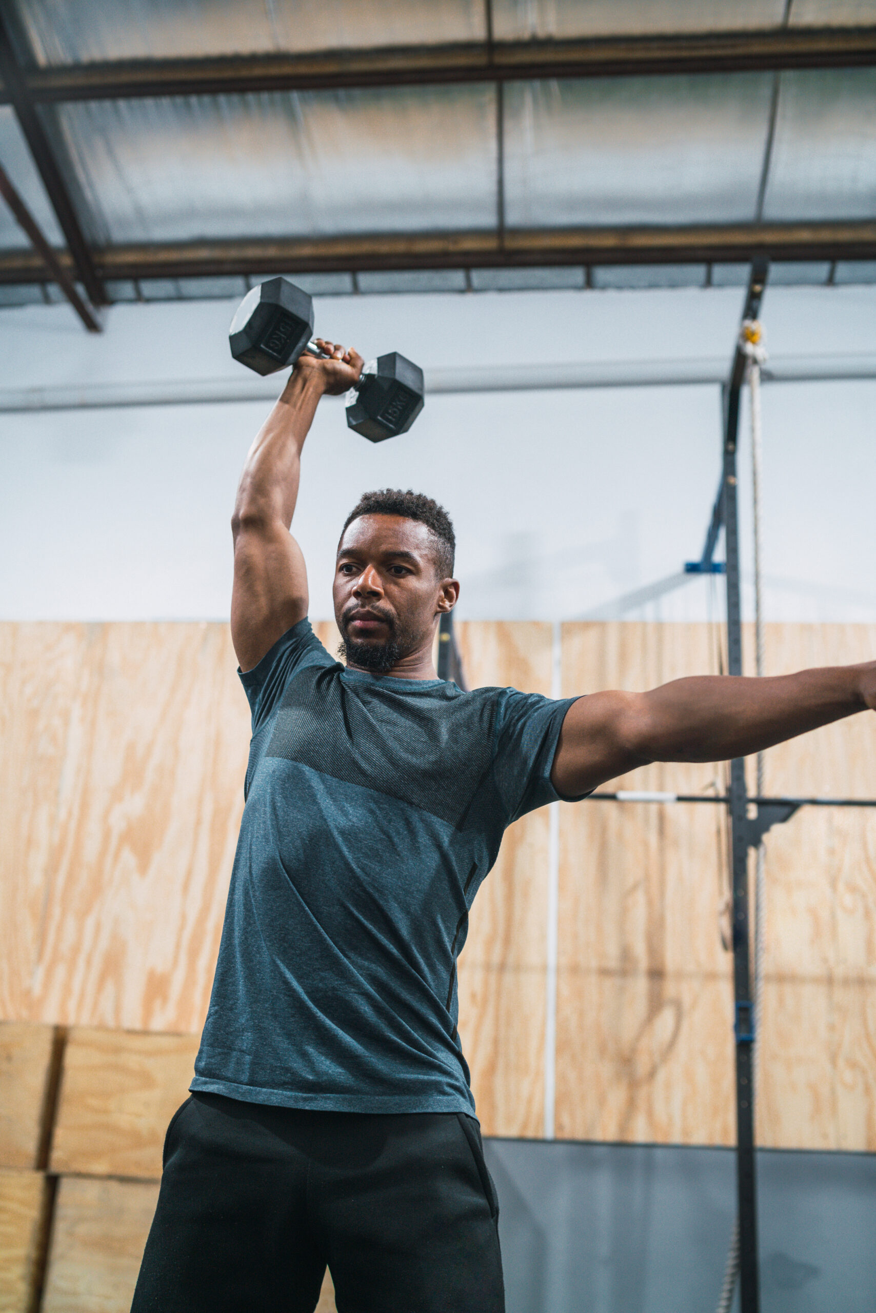 Portrait of young crossfit athlete doing exercise with dumbbell at the gym. Crossfit, sport and healthy lifestyle concept.